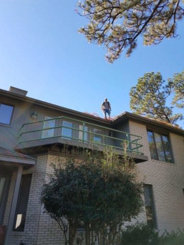 man on roof cleaning gutters